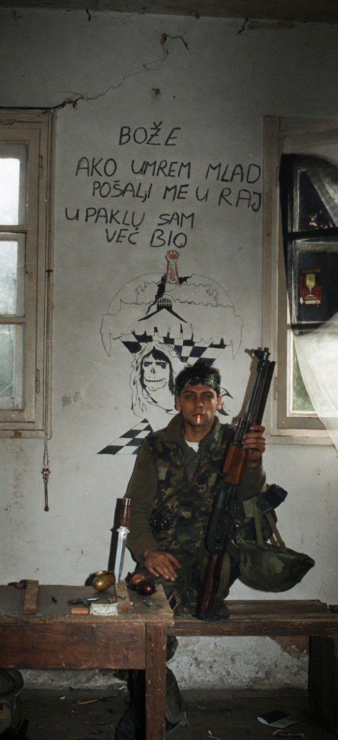 Croatian soldier in the 90s Croatian War of Independence, standing before a sign that reads: “God, if I die young, take me to heaven. I’ve already experienced hell.